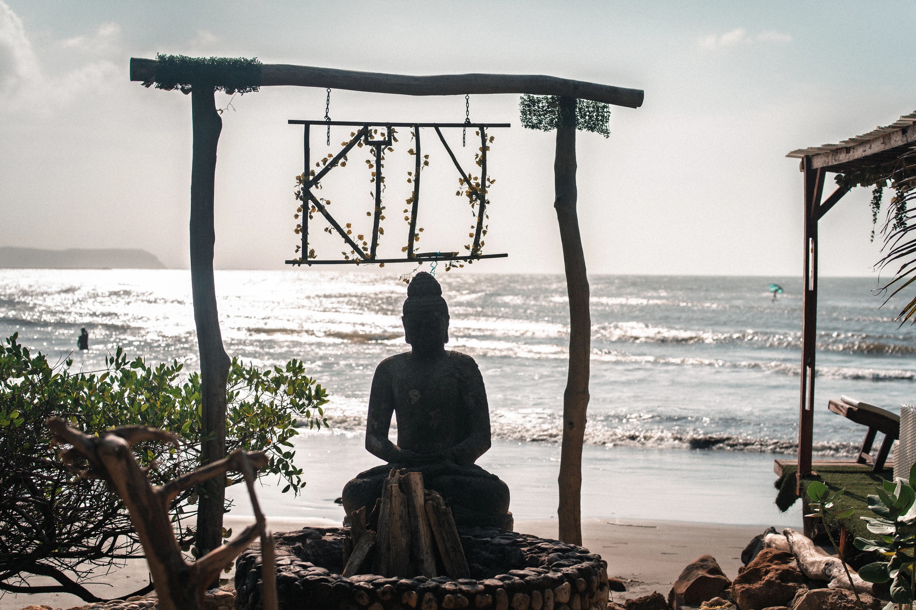 A seated figure facing the ocean through a wooden frame