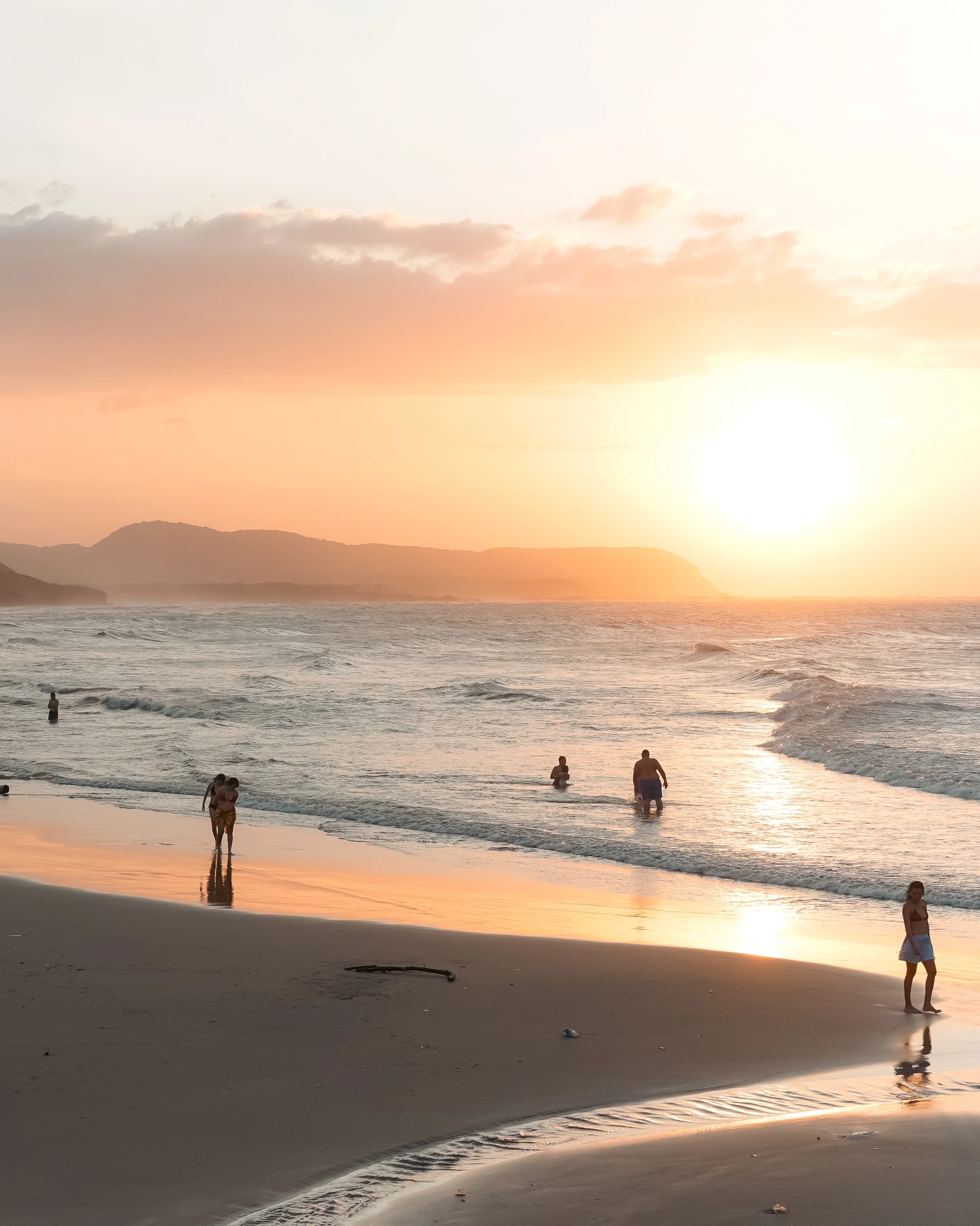 Sun setting beyond a beach and mountains