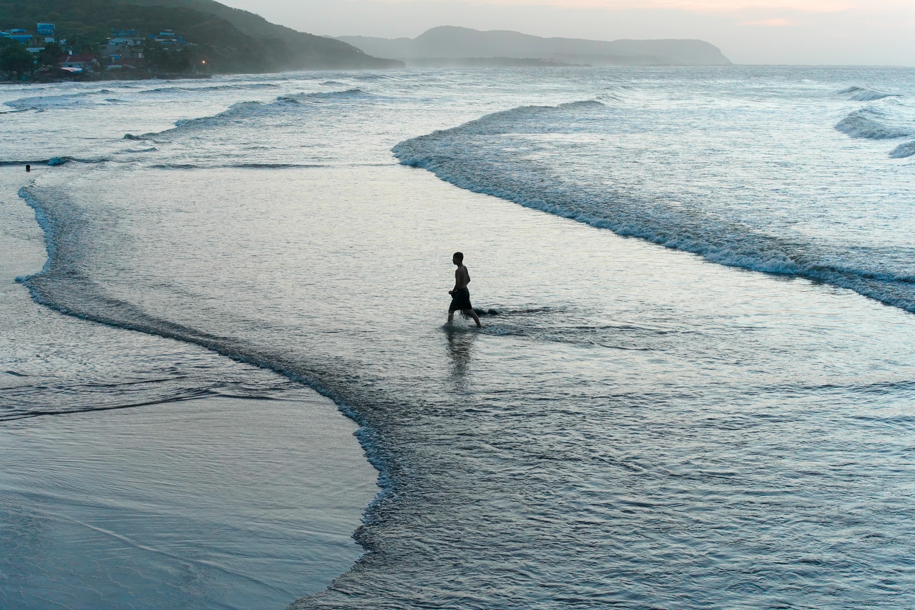 A lone figure where the waves meet the shore