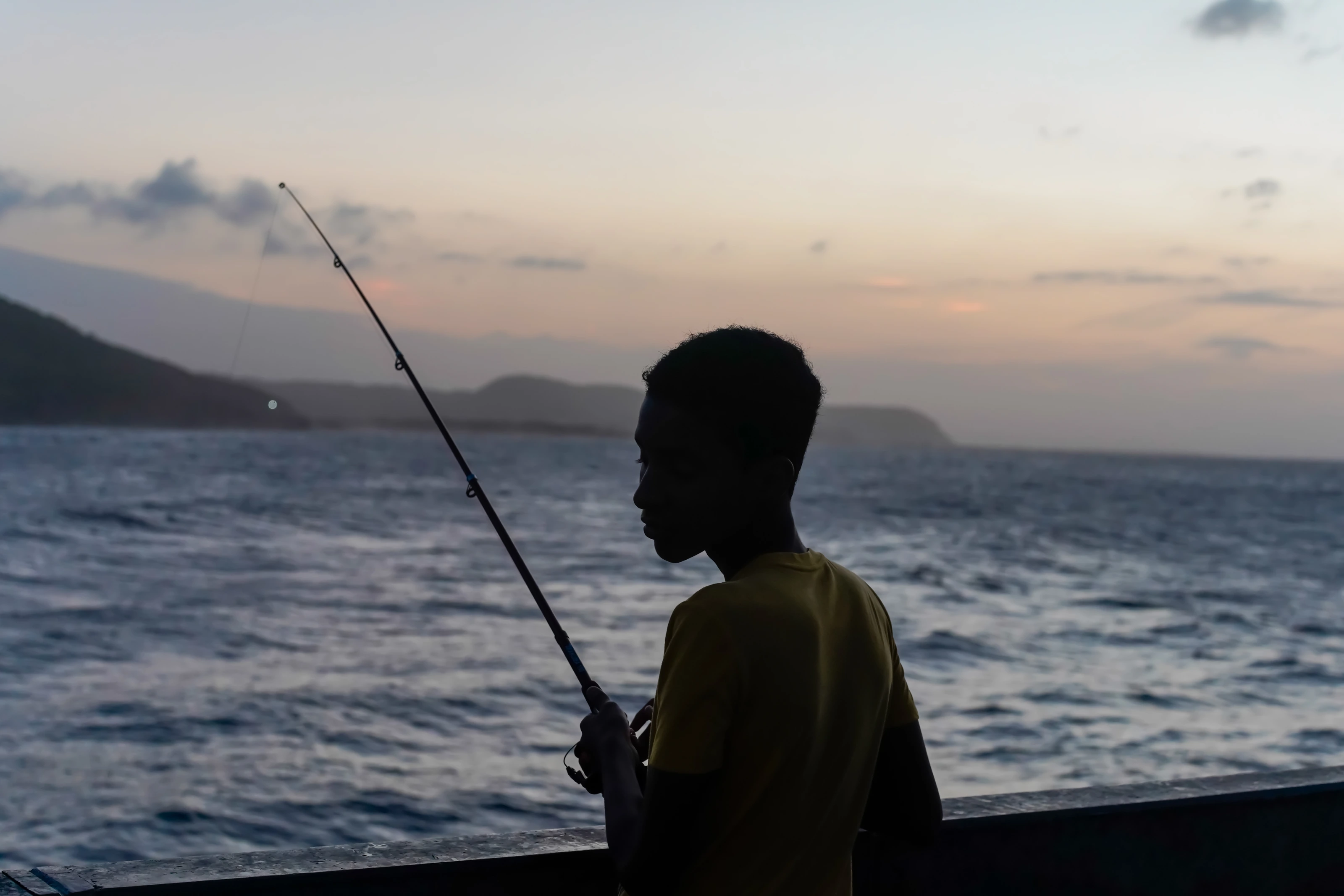 A fisherman silhouetted against the evening sky